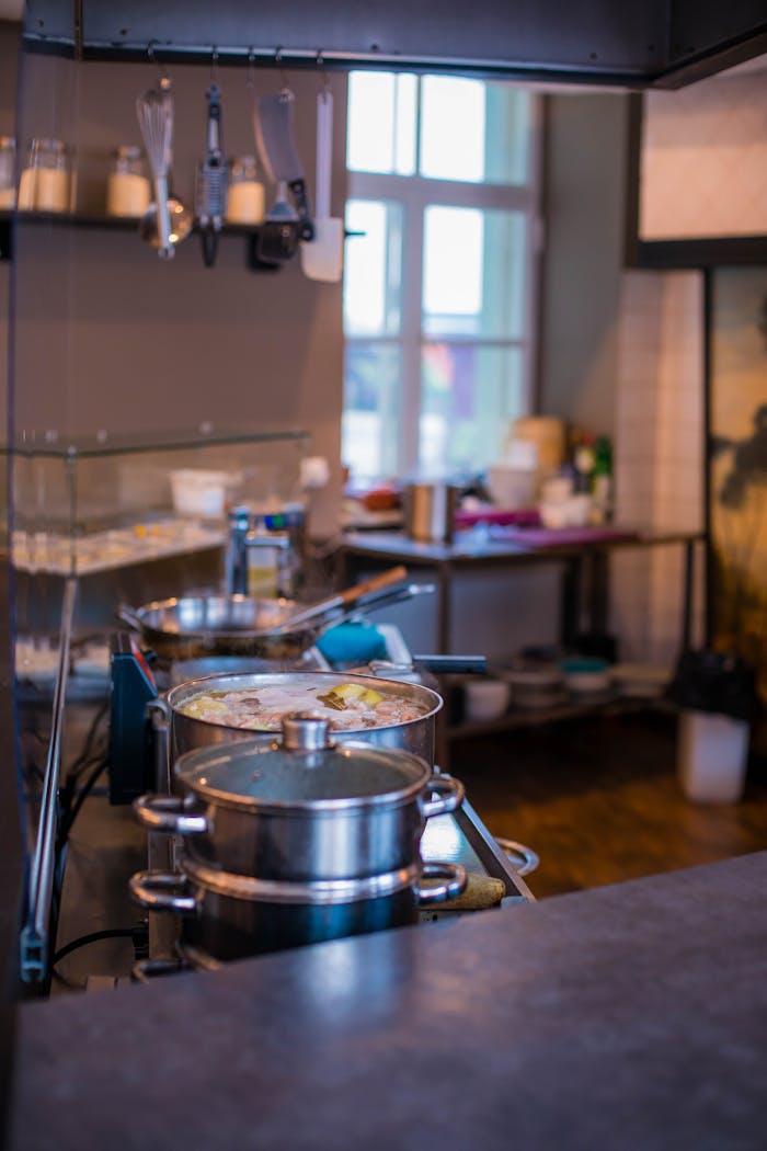 who-we-are A cozy kitchen with stainless steel cookware simmering on the stove, with a warm ambiance.