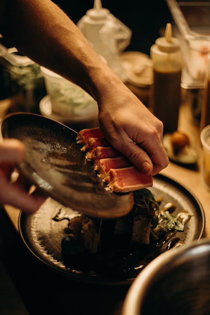 our-story A chef artfully plates fresh sashimi with care in a warm kitchen atmosphere.