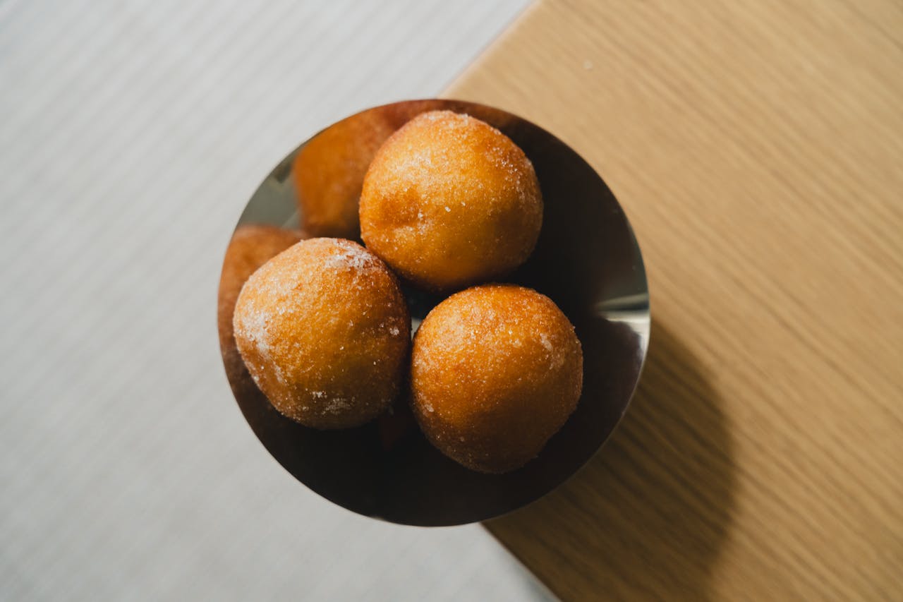about-us Top-down view of sugar-coated quark balls in a brown bowl on wooden table.
